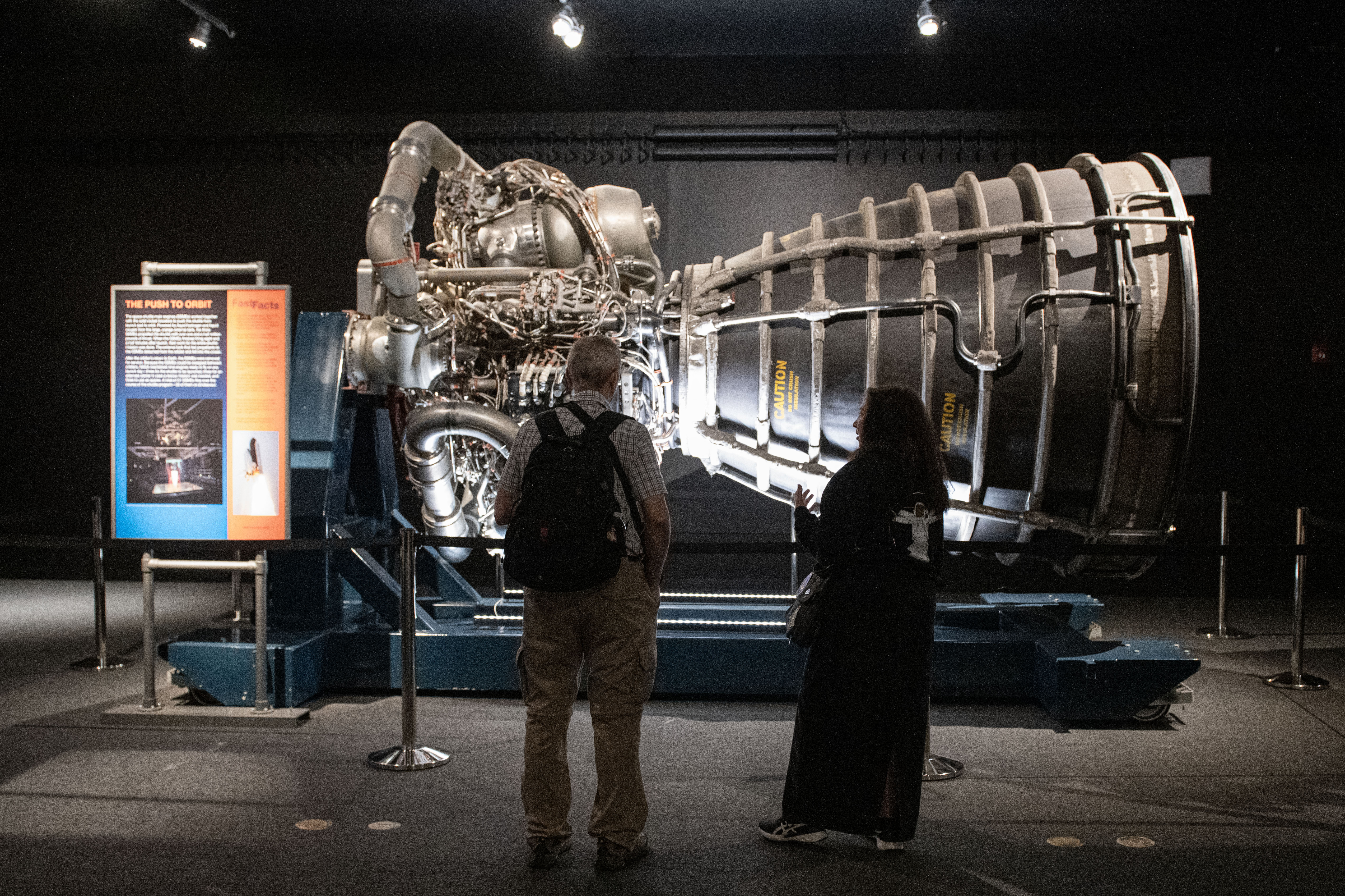 Visitors silhouetted as they observe the space shuttle main engine.