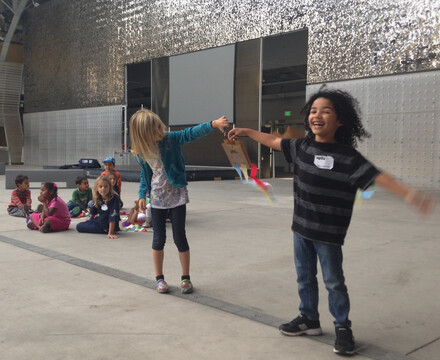Two happy kids hold hands among friends in a science camp class
