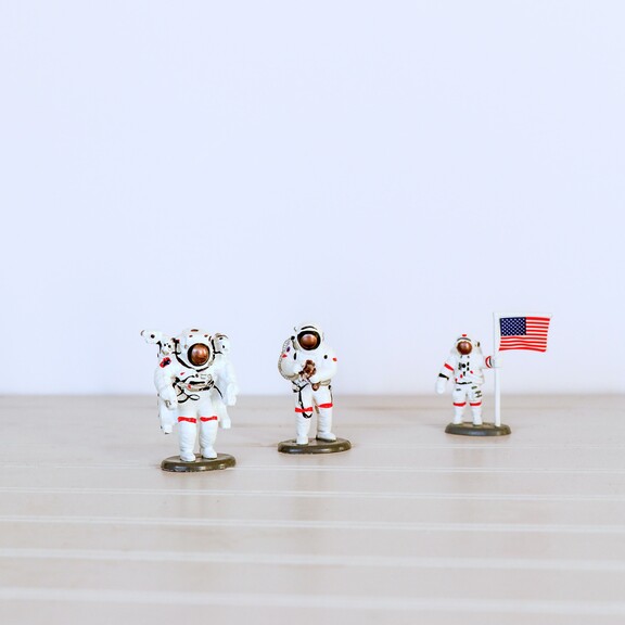 Three US astronaut plastic toys on light tabletop
