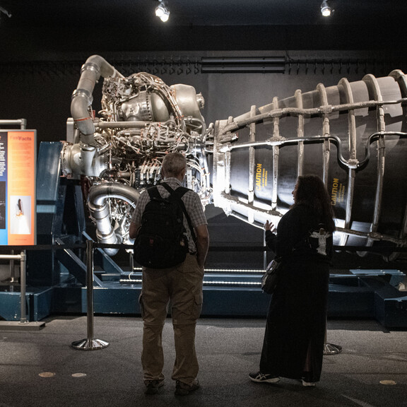 Visitors silhouetted as they observe the space shuttle main engine.