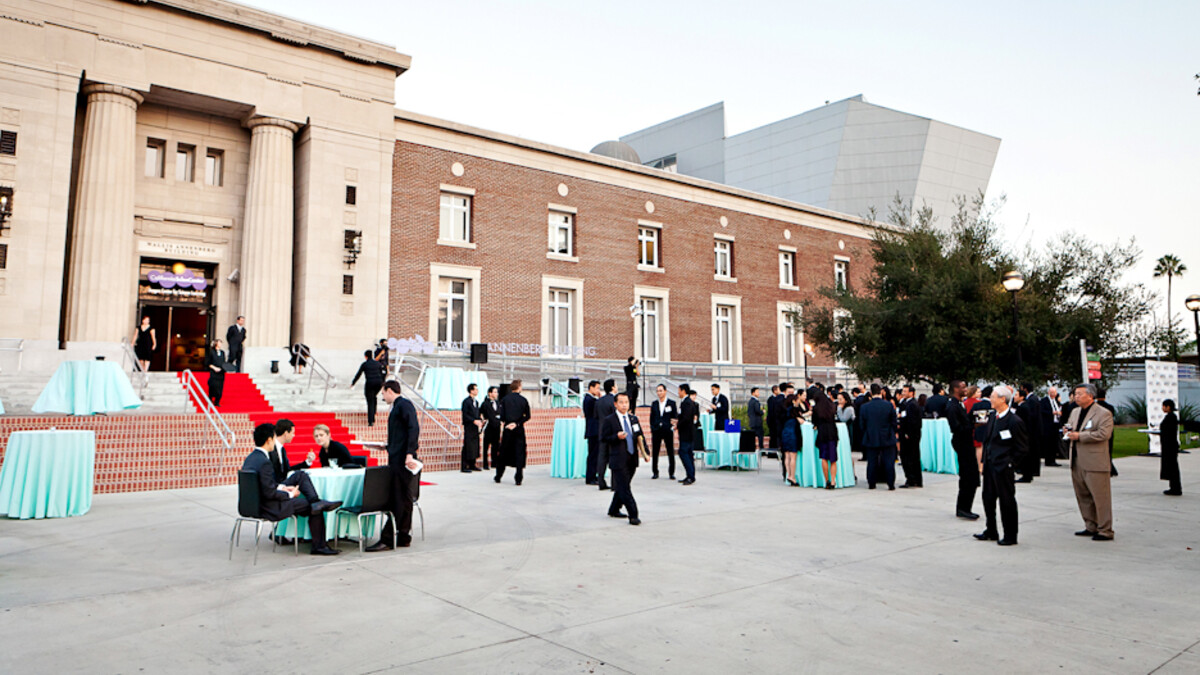 Event guests arriving at the Wallis Annenberg Building entrance with red carpet draped steps and robin egg blue cocktail tables