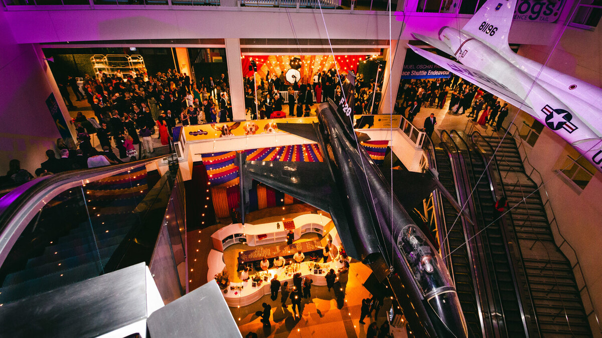 Aerial view of carnival themed cocktail party in the Ahmanson Building with purple and amber lighting at dusk