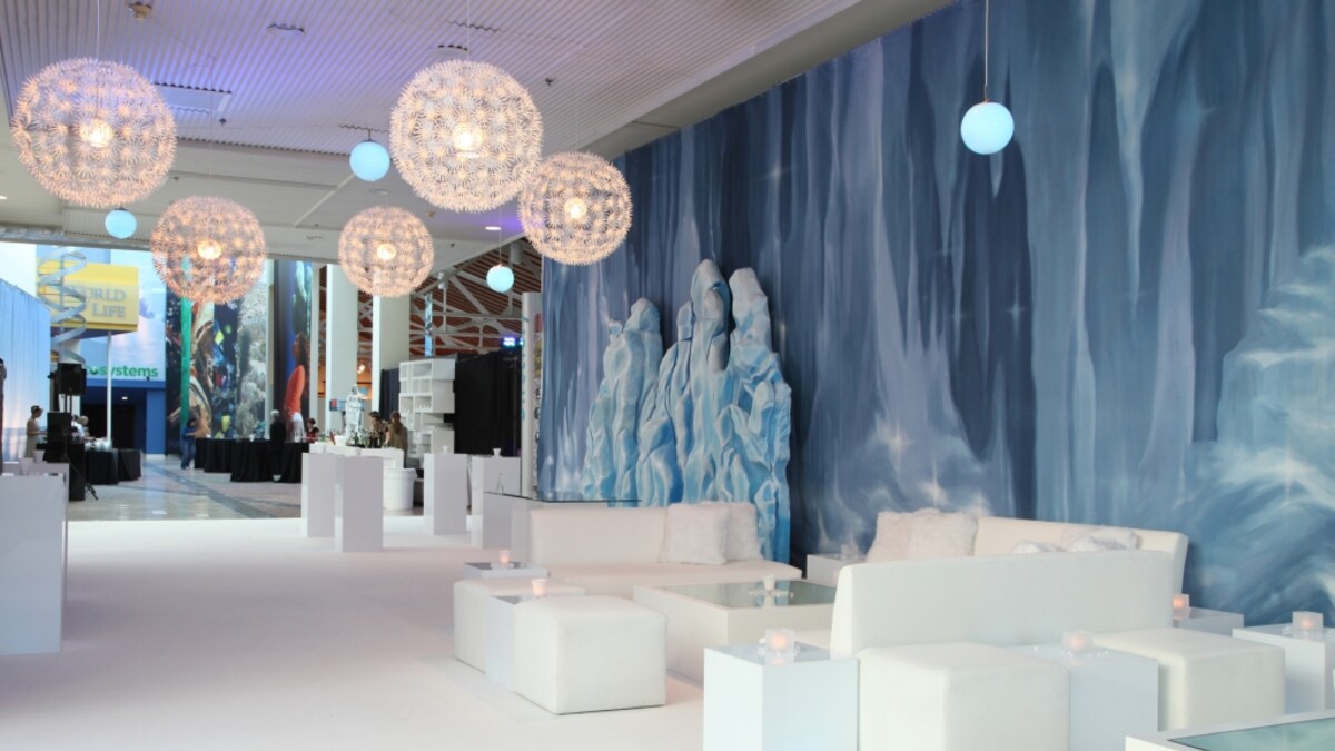 White lounge furniture, blue icy backdrops, and round white starburst chandeliers on Disney Court for arctic cocktail party