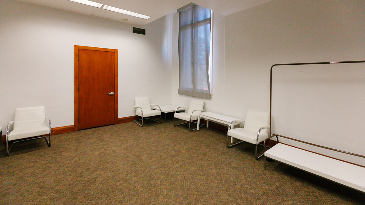 MUSES Lounge - Small empty greenroom with white lounge chairs and coffee tables