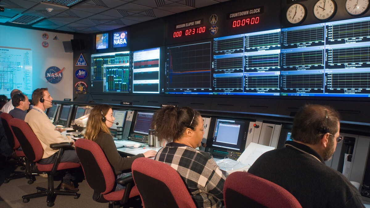 Staff members sit at their stations in front of a wall of monitors
