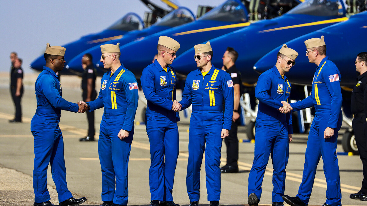 Blue Angels pilots shake hands in front of their planes.