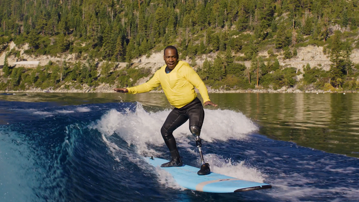 Man with a prosthetic limb wakesurfing in a lake.