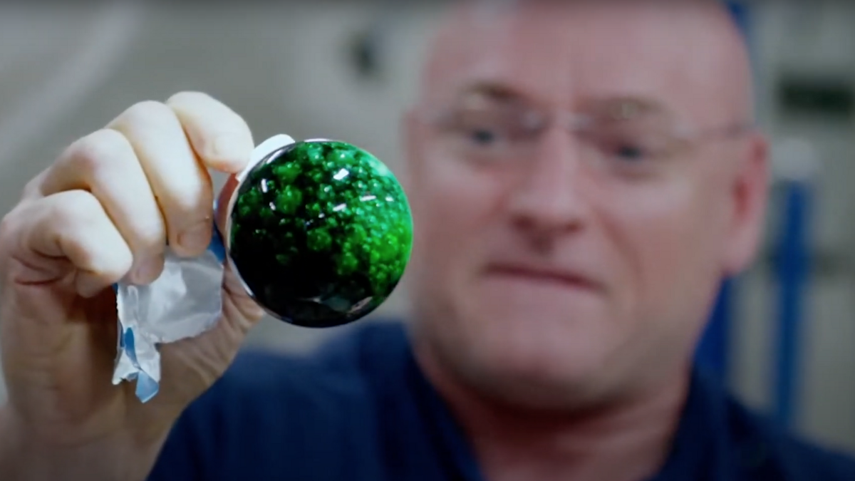 An astronaut experiments with a ball of liquid in microgravity.