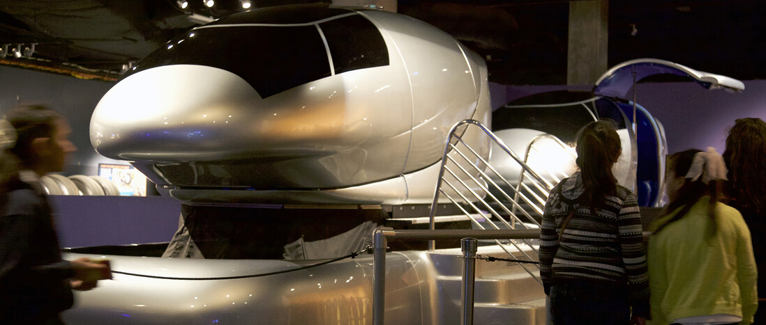 Children gather around silver motion simulators in the Endeavour Together exhibit gallery