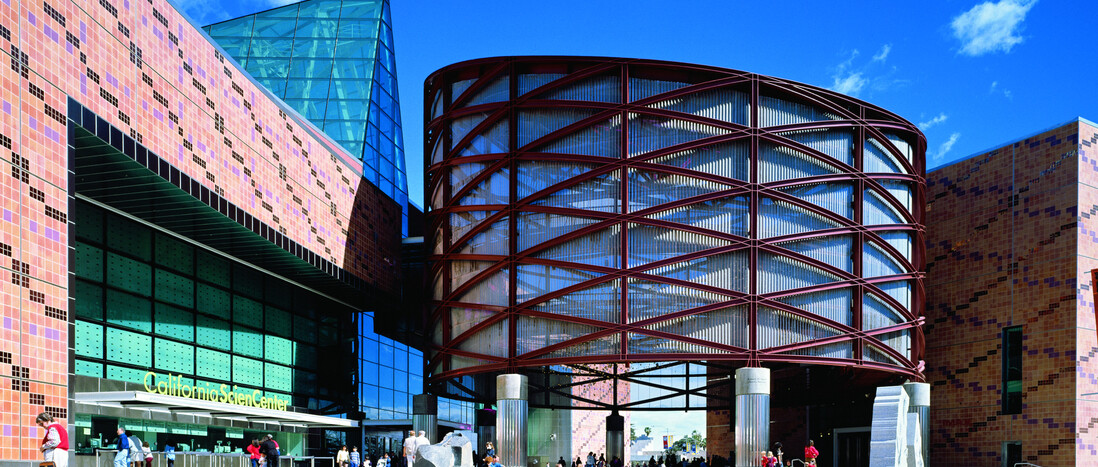 Exterior photo of the California Science Center building with crowds in the distance.